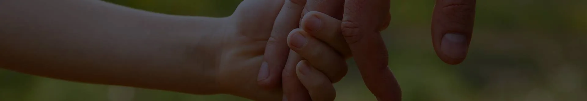 Parent holding a young child's hand outdoors