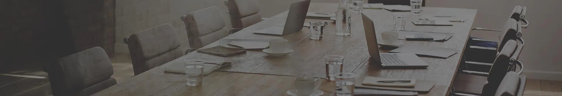 Empty conference table set with laptops, notebooks and coffee cups